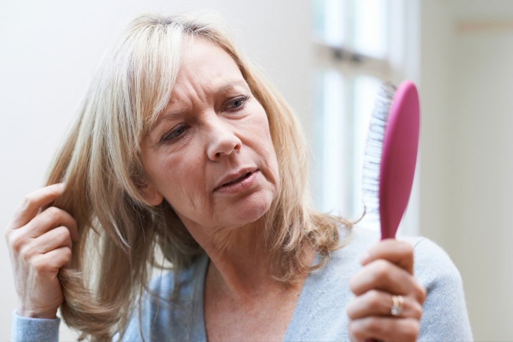 Woman looking at her hairbrush, concerned about hair loss