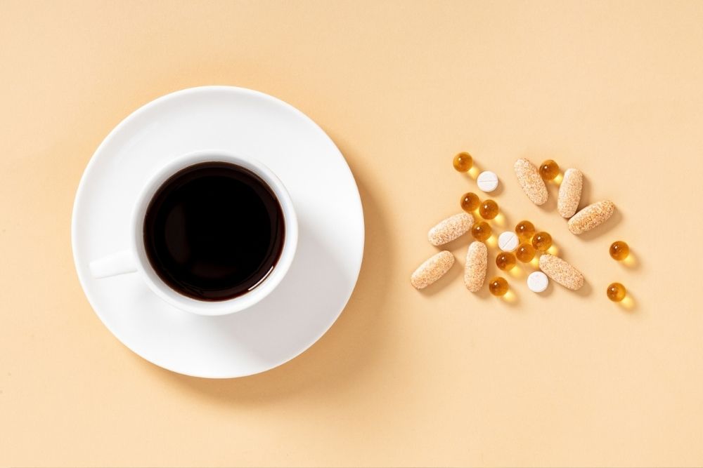 Cup of coffee next to vitamin supplements Cup of coffee next to vitamin supplements