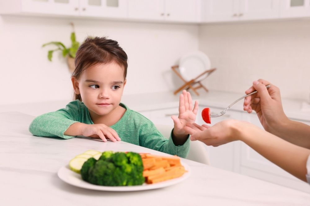 Young girl refusing to eat her vegetables at dinner Young girl refusing to eat her vegetables at dinner