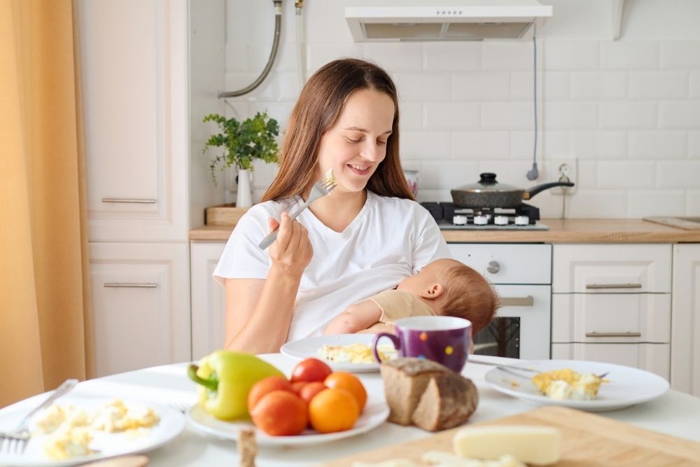 New mother breastfeeding at a table with a healthy breakfast New mother breastfeeding at a table with a healthy breakfast