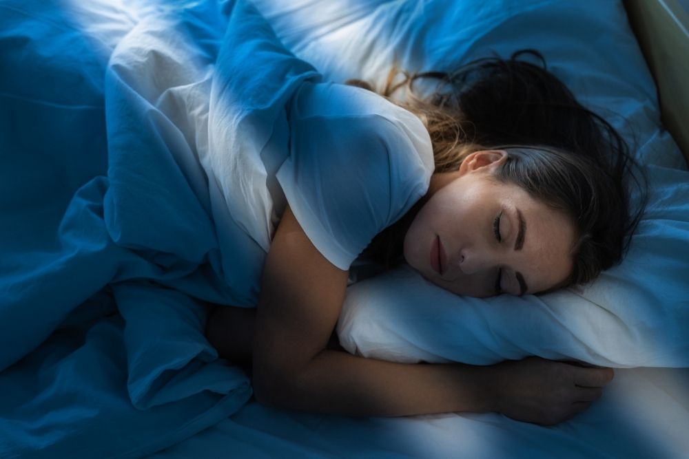 Woman sleeping peacefully in bed at sunrise